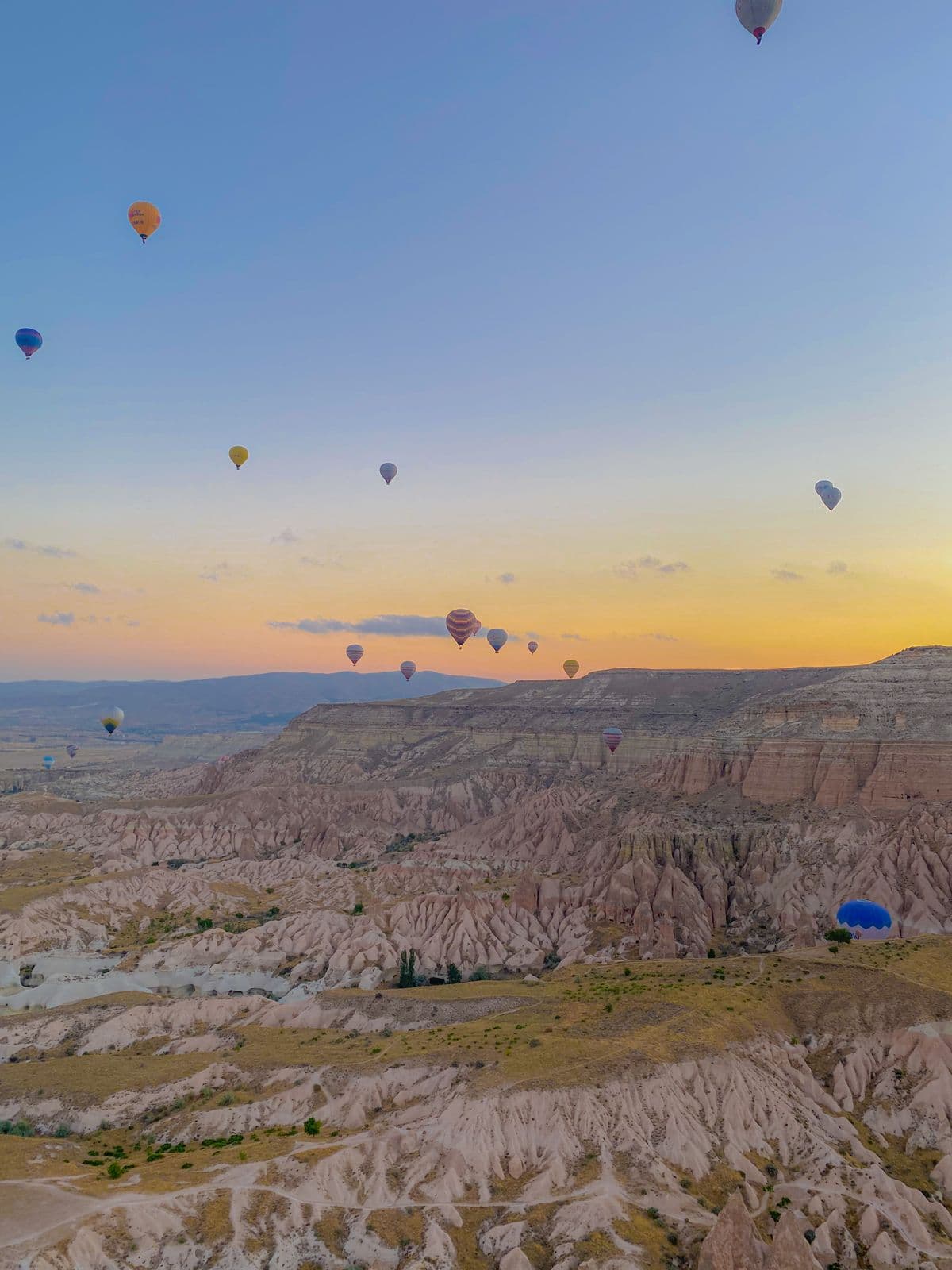 A hot air balloon basket floating above Cappadocia's valleys at sunrise