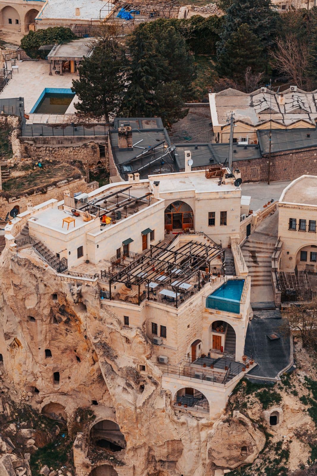 Aerial view of a cave hotel with a pool among the rock formations of Cappadocia