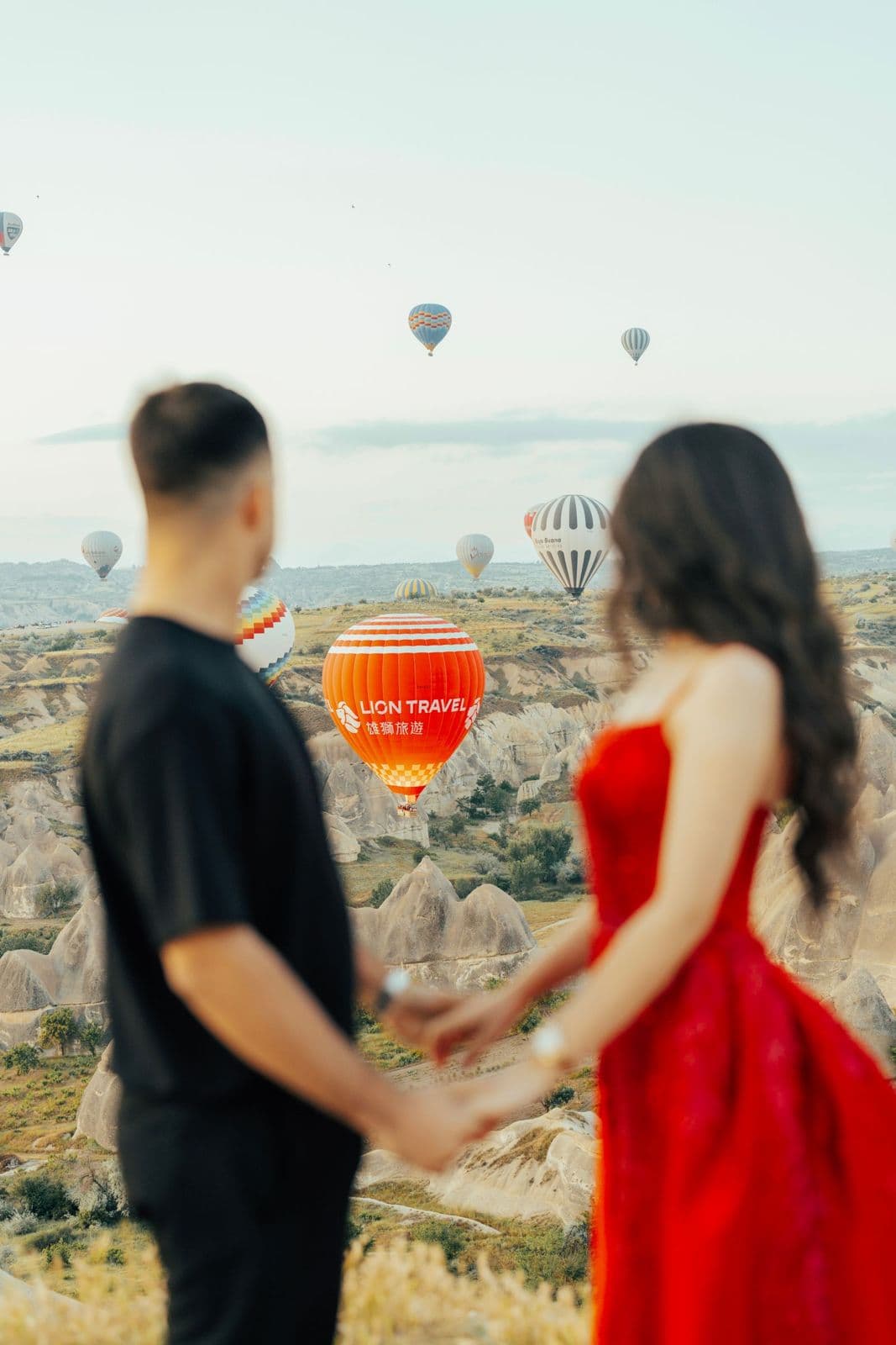 A couple holding hands under hot air balloons