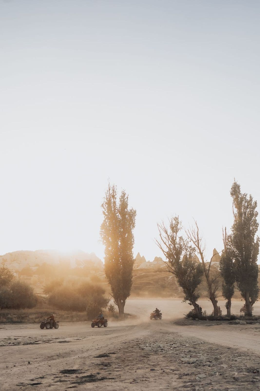 ATV riders on a dusty trail in Rose Valley, Cappadocia, at sunset